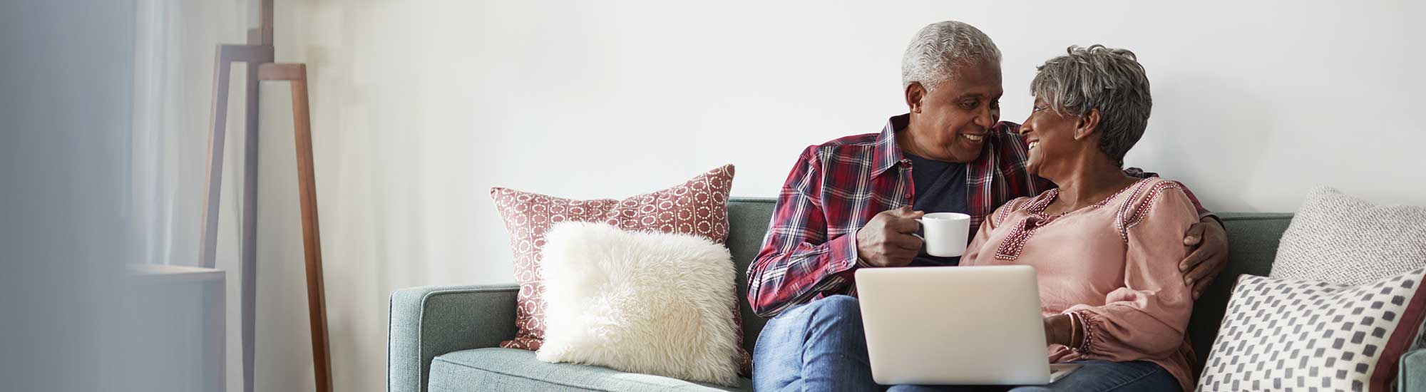 older couple smiling at each other with laptop